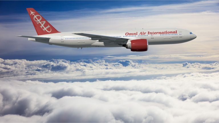 Omni Air International Boeing 777 in flight above the clouds